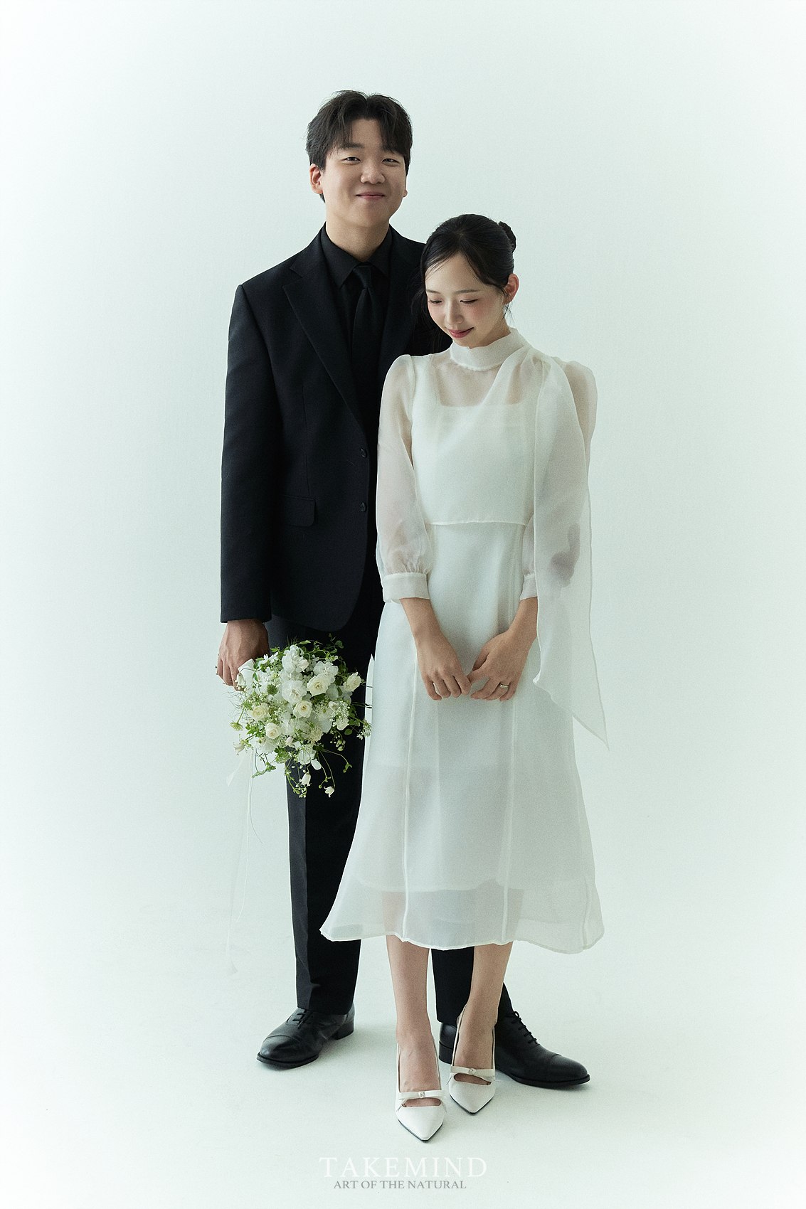 벽돌 담장과 초록 식물 앞에서 함께 웃고 있는 왕혁과 수민